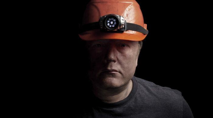 portrait of a man with a hard hat looking solemn.