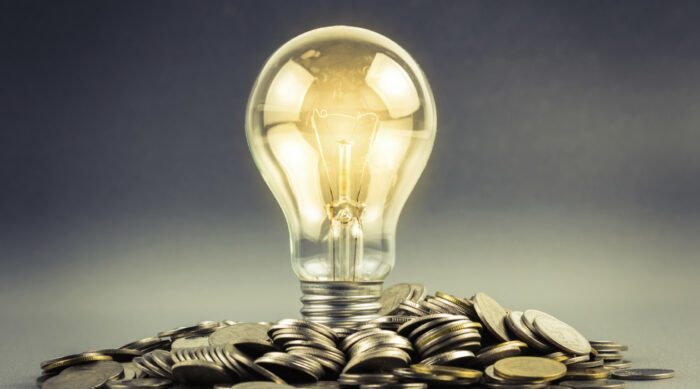 lightbulb lit above coins showing power of energy.