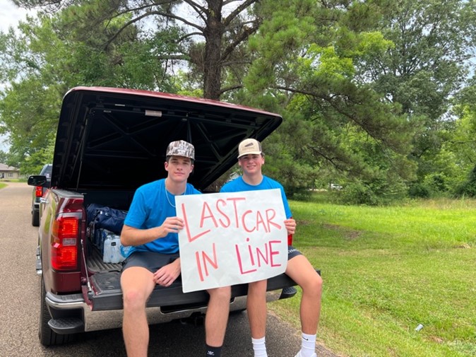 Two young men wait in line for discounted gas at AFP-Mississippi's True Cost event in Forest, MS on June 30. Their sign reads, "Last car in line." Like many customers, these two gentlemen were waiting for relief from the rising cost of gas in 2022. 