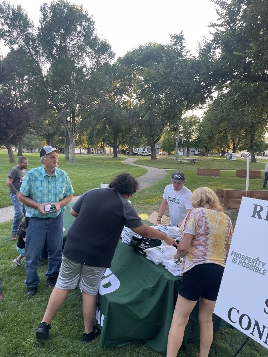 Concerned citizens convene at the Prosperity Is Possible display table to discuss energy solutions for high energy costs at the gas pump. 